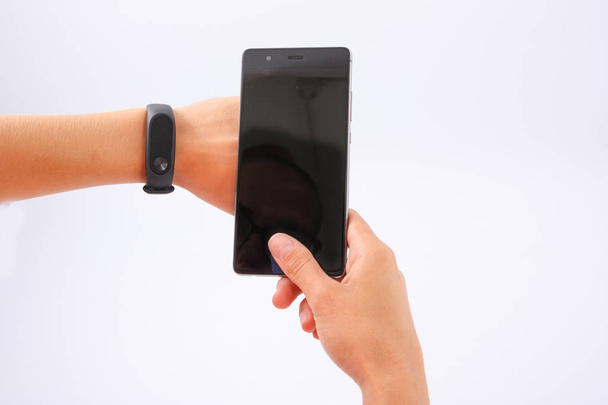 Telefon v ženských rukou na bílém a fitness náramek - Fotografie, Obrázek