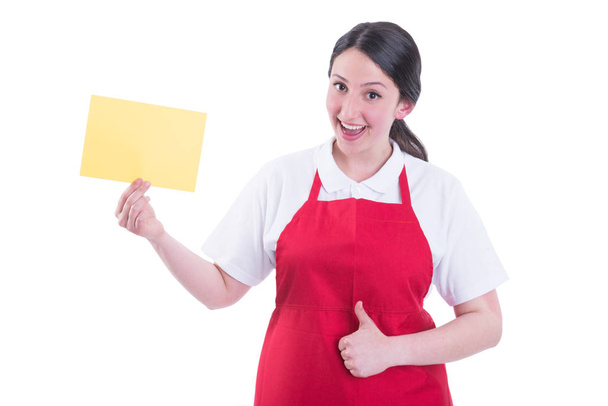 Vrolijke vrouwelijke verkoper met lege papier weergegeven: thumbup - Foto, afbeelding