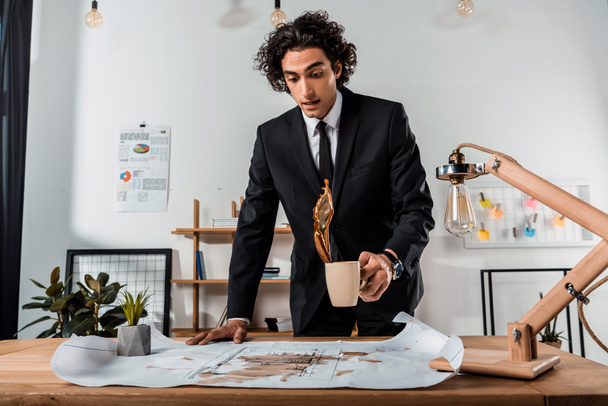 businessman pouring coffee on blueprints - Foto, afbeelding