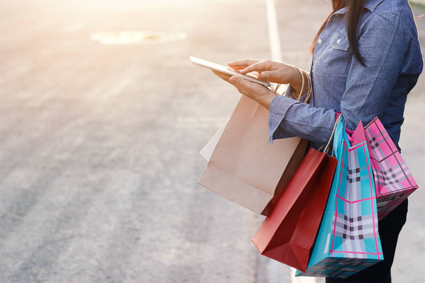 mulher com sacos de compras, usando smartphone ou tablet
 - Foto, Imagem