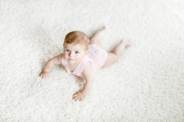 Little funny baby girl lifting body and learning to crawl. - Photo, Image