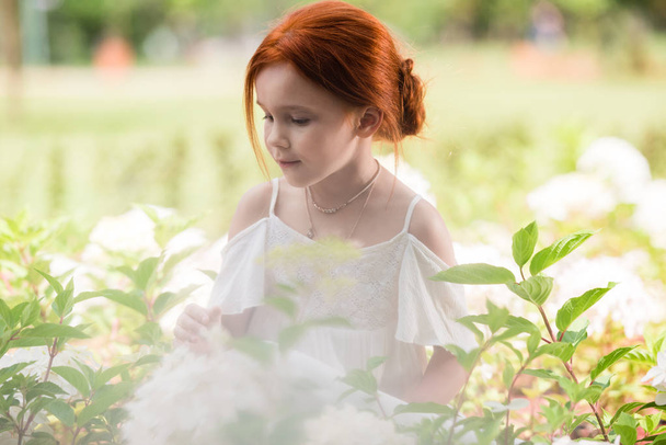 redhead girl in flower bed - Foto, imagen