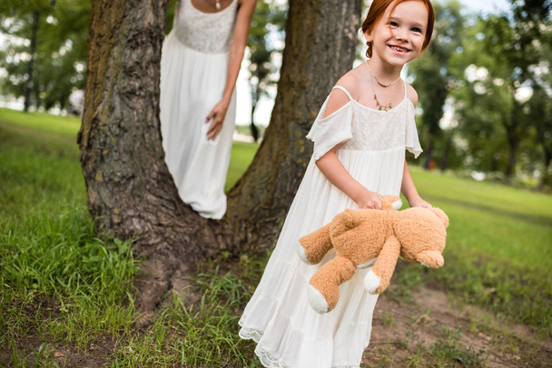 mother and daughter with teddy bear in park - Photo, Image