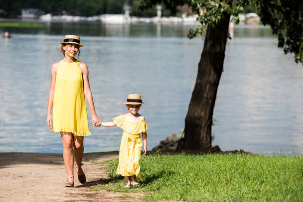 mother and daughter walking at riverside - Фото, изображение