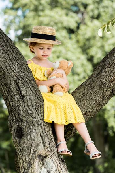 girl with teddy bear sitting on tree - Zdjęcie, obraz