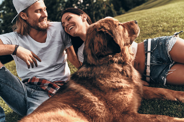 couple lying on grass with dog - Foto, immagini