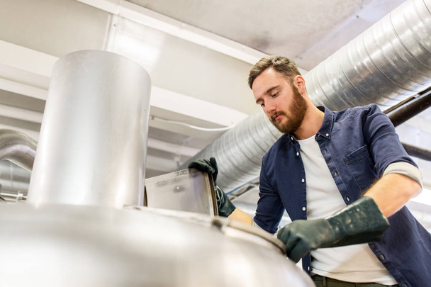 man working at craft brewery or beer plant - Foto, Bild