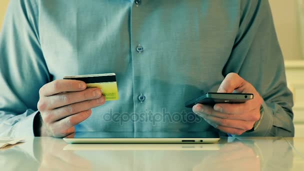 Közelkép ember használ hitelkártya tabletta és okos-telefon részére Online Bevásárlás - Felvétel, videó