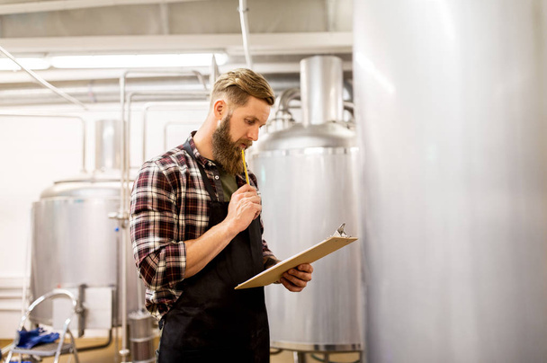 man with clipboard at craft brewery or beer plant - Zdjęcie, obraz