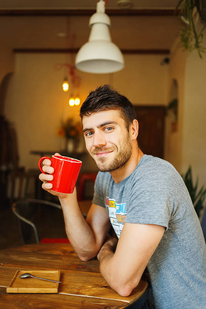 Red cup in the hands of a smiling Handsome - 写真・画像