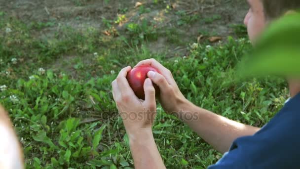 Muž se snaží rozdělit červené jablko - Záběry, video