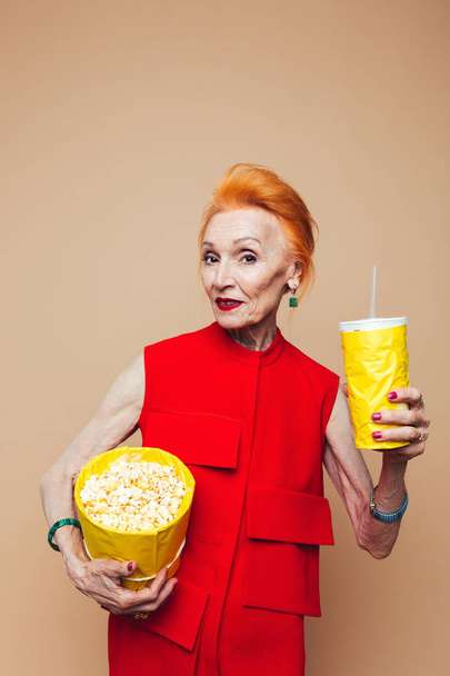 Smiling mature redhead fashion woman eating popcorn - Photo, image