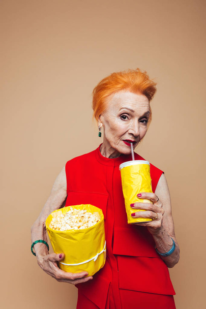Smiling mature redhead fashion woman eating popcorn - Φωτογραφία, εικόνα