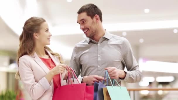 happy young couple with shopping bags in mall - Filmati, video