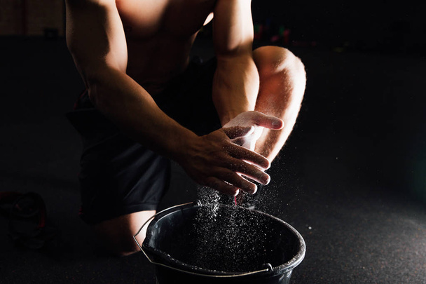 Fitness model trainer rubs his hands with chalk and talc so that fingers do not slip or slide. - Foto, Imagem