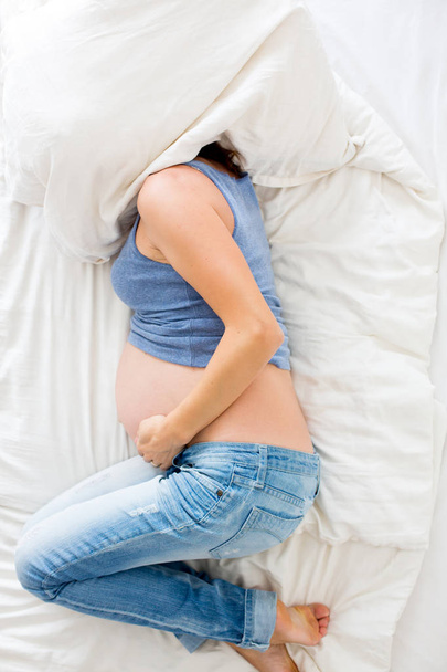Mujer embarazada joven acostada en la cama con dolor
 - Foto, imagen