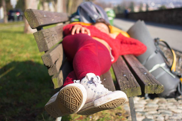 Girl sleeping on wood bench outdoors. Outside female lying - Photo, Image