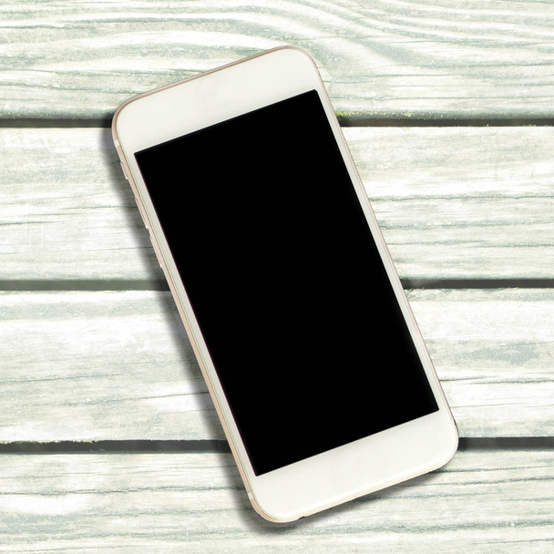 Smartphone bianco con schermo nero su sfondo in legno bianco. Smartphone schermo nero. Mockup schermo del telefono con posto di testo. Dispositivo personale piatto lay vista dall'alto. Modello di banner estivo modello gadget
 - Foto, immagini