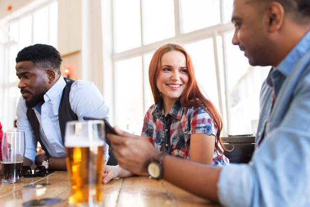 happy friends with tablet pc drinking beer at bar - Φωτογραφία, εικόνα