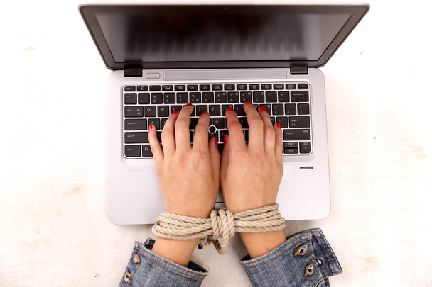 現代の奴隷制度の概念。コンピューターで作業する女性の手縛ら  - 写真・画像