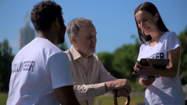 Χαρούμενη νέοι εθελοντές χρησιμοποιώντας tablet με ένας ανώτερος άνθρωπος - Πλάνα, βίντεο