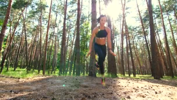 Beautiful, athletic, sexy young woman, coach, instructor, performs exercises, doing exercises with fitness trx system, TRX suspension straps. In pine forest, in summer, in sun rays. - Felvétel, videó
