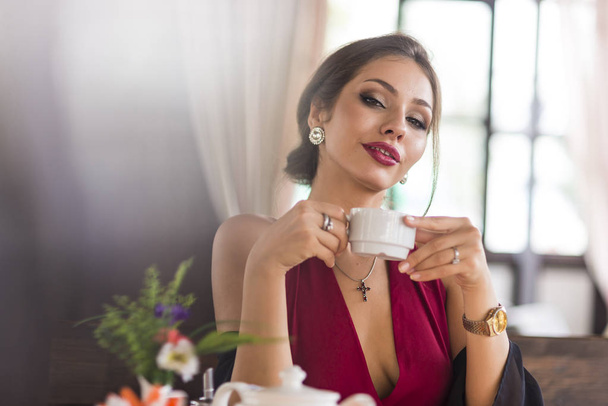 junge Geschäftsfrau grinst Kaffee in einem Café. lächelt und flirtet. Blicke in die Kamera - Foto, Bild
