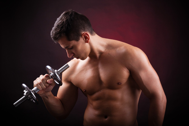 Image of a muscular young man lifting weights on black backgroun - Φωτογραφία, εικόνα