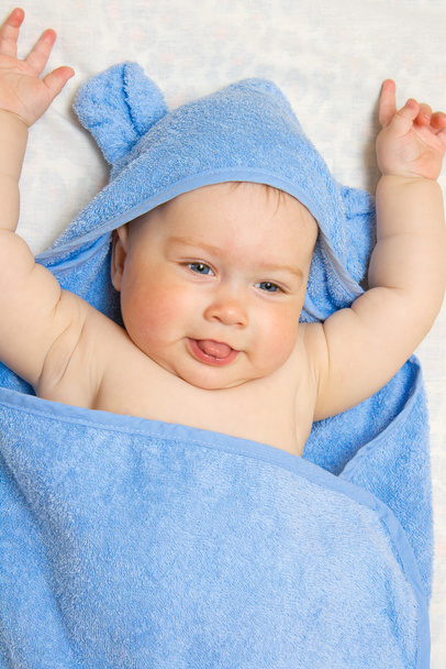Small smiling baby in blue towel - 写真・画像