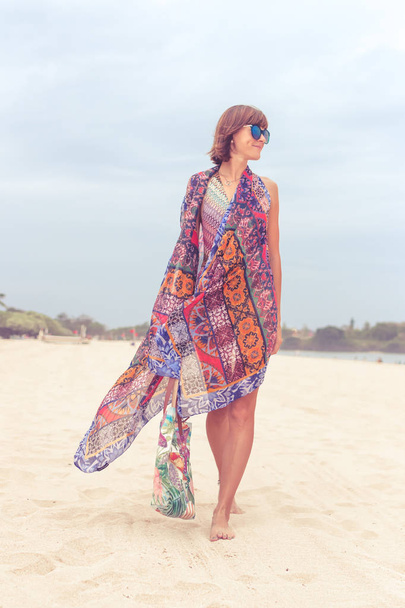 Touristin, die mit Sonnenbrille und Strandtasche an einem tropischen Sommerurlaubsstrand spazieren geht und sich im Urlaub entspannt. junge Dame in luxuriöser Mode Beachwear, Bali Island, Indonesien. - Foto, Bild