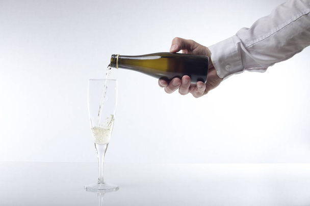 Ένας σερβιτόρος που γεμίζει ένα ποτήρι κρασί με σαμπάνια - Φωτογραφία, εικόνα