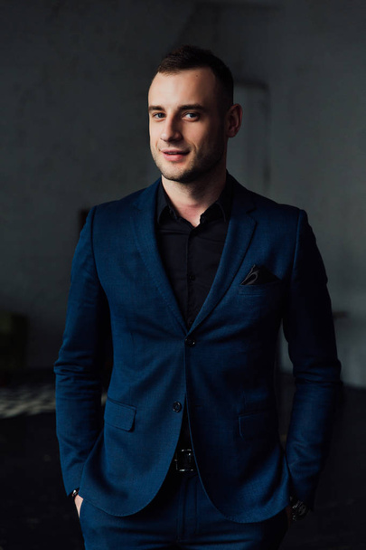 Young attractive and confident businessman in blue suit and black tie. - Фото, зображення
