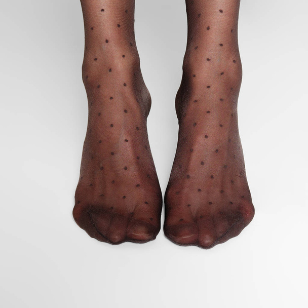 Top view of female legs in transparent tights with a classic polka dot pattern - Fotó, kép