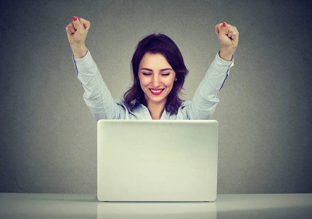 Successful woman winner with arms raised looking at laptop  - 写真・画像