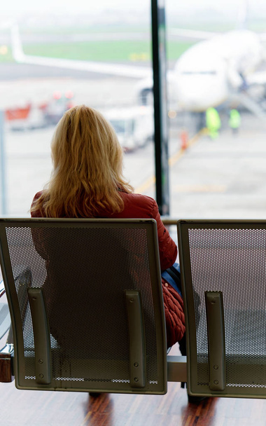 Mulher sentada e esperando seu voo no aeroporto de Milão
 - Foto, Imagem