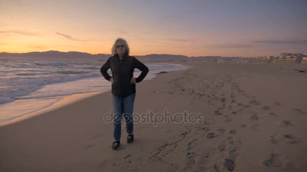 Actieve aantrekkelijk rijpe vrouw lopen op het strand bij zonsondergang - Video