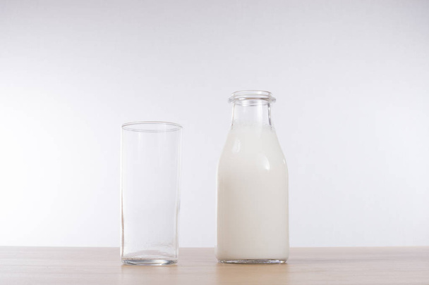Tall glass alongside a bottle of milk - Photo, Image