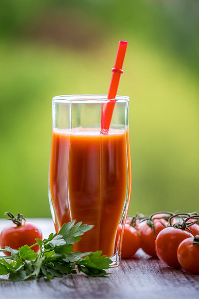 Tomato juice and tomatoes on a green background. - Photo, image