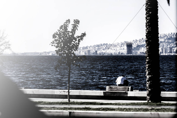 Mies istuu yksin Izmirin rannikolla (Turkki)
) - Valokuva, kuva