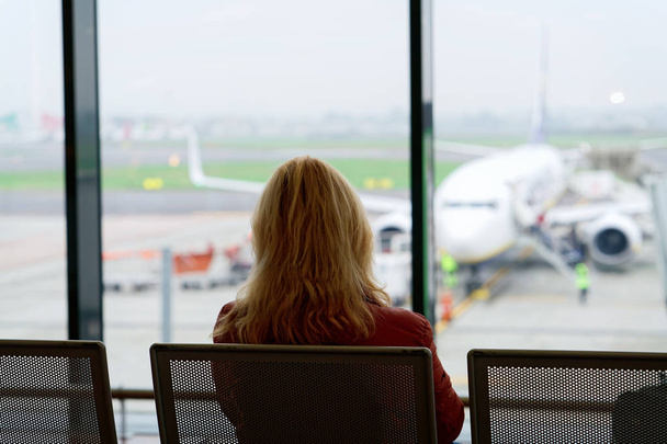 Mujer sentada y esperando su vuelo en el aeropuerto de Milán
 - Foto, Imagen