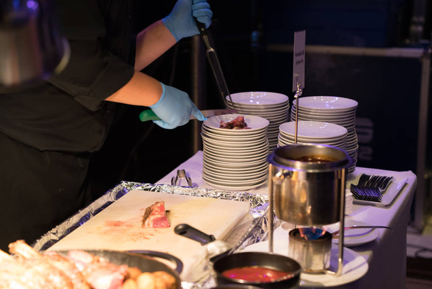 Chef del hotel rebanando costilla de repuesto de ternera a la parrilla con cuchillo largo y tenedor
 - Foto, Imagen