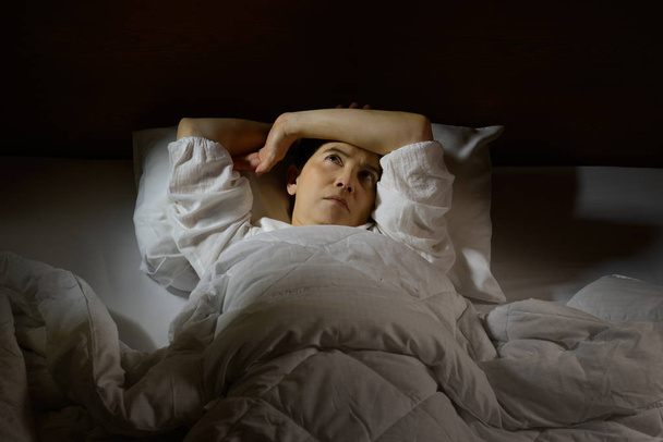 mujer con insomnio acostada en la cama con los ojos abiertos - Foto, imagen