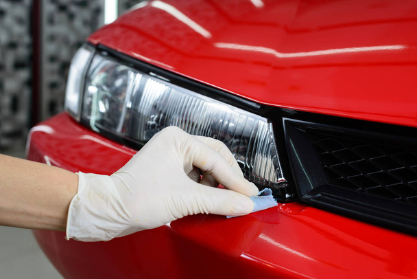 Auto detaillering serie: Close-up van hand coating rode auto bumper - Foto, afbeelding