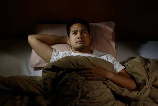 Homem deprimido sofrendo de insônia deitado na cama
 - Foto, Imagem