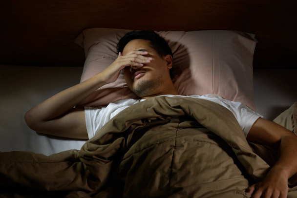 Przygnębiony człowiek cierpi na bezsenność, leżąc w łóżku - Zdjęcie, obraz