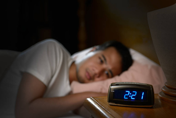 Masentunut mies kärsii unettomuudesta makaa sängyssä
 - Valokuva, kuva