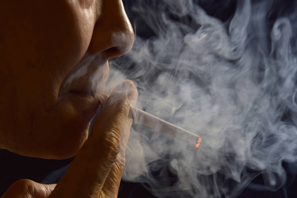 Чоловік палить цигарку в оточенні диму
 - Фото, зображення