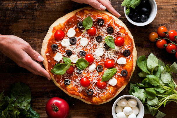 Hands holding homemade italian pizza - 写真・画像