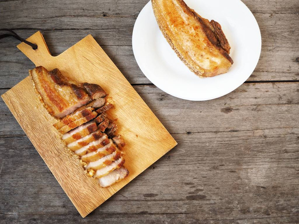 vista elevada del vientre de cerdo a la parrilla en la tabla de cortar y la placa en la cocina
 - Foto, Imagen