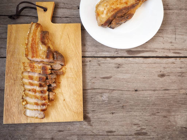 vue du dessus du ventre de porc grillé sur une planche et une assiette en bois dans la cuisine
 - Photo, image